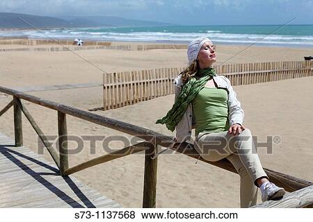 Stock Photo - Woman in Barbate beach and wooden barriers supposed to hinder the sand from invading the promenade. Barbate. CBdiz province. Andalusia. Spain. Fotosearch