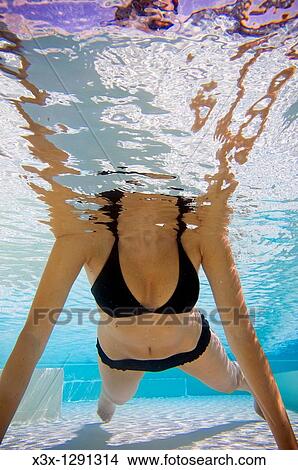 Woman in bathing suit swimming in a pool seen from underwater View Large Photo Image Picture - Woman in bathing suit swimming in a pool seen from underwater. Fotosearch