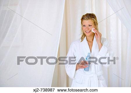Stock Photo - Woman in bathrobe cleaning her face. Fotosearch