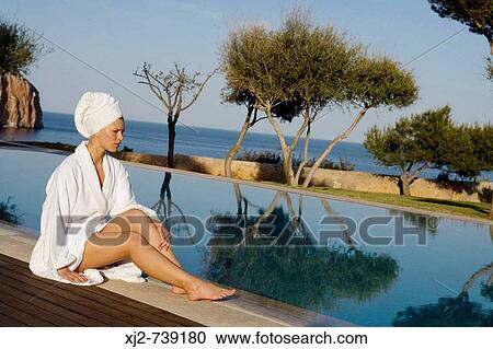 Woman in bathrobe sitting by the swimming pool View Large Photo Image Stock Image - Woman in bathrobe sitting by the swimming pool. Fotosearch