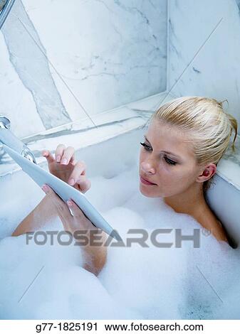 Woman in bathtub with tablet View Large Photo Image Stock Image - Woman in bathtub with tablet. Fotosearch