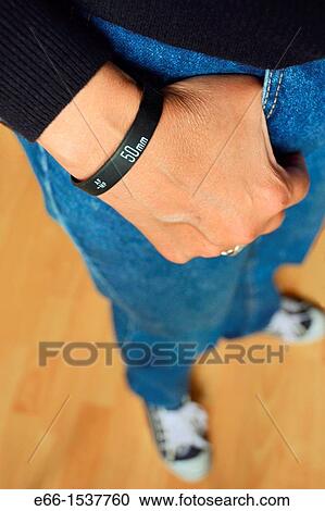 Woman in blue jeans, black sweater and sneakers, wearing a? Lens Bracelet? designed by Adam Elmakais - with shallow depth of field View Large Photo Image Stock Image - Woman in blue jeans, black sweater and sneakers, wearing a? Lens Bracelet? designed by Adam Elmakais - with shallow depth of field. Fotosearch