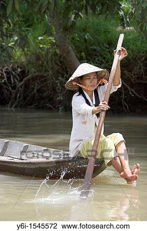 Woman in conical hat paddling boat through Mekong Delta backwaters Vietnam View Large Photo Image Stock Image - Woman in conical hat paddling boat through Mekong Delta backwaters Vietnam. Fotosearch