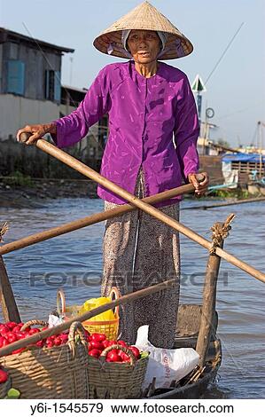 Stock Photo - Woman in conical hat rows boat with baskets of wax apples Cai Ran floating market near Can Tho Vietnam. Fotosearch