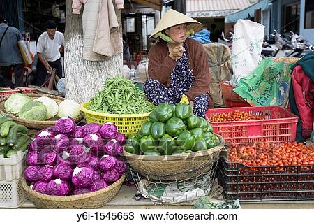 Stock Image - Woman in conical hat selling vegetables Dalat south east Vietnam. Fotosearch