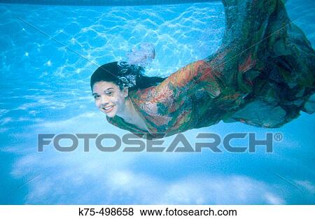 Stock Photo - Woman in dress swimming underwater. Fotosearch