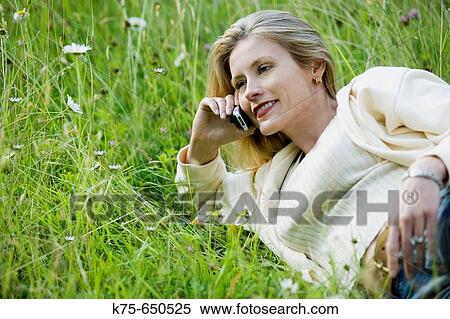 Stock Photography - woman in field using cell phone. Fotosearch