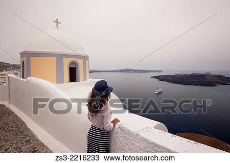 Stock Image - Woman in front of a yellow domed church in Fira town looking at the sea, Santorini, Cyclades Islands, Greek Islands, Greece, Europe.. Fotosearch