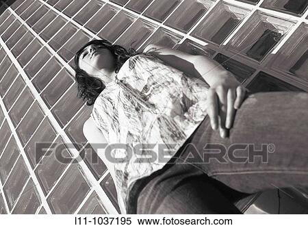 Stock Photography - Woman in front of bottle glass building. Fotosearch