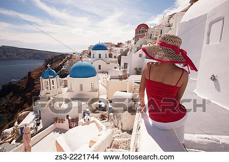 Picture - Woman in front of the blue domed church in Oia town looking at Caldera, Santorini, Cyclades Islands, Greek Islands, Greece, Europe.. Fotosearch