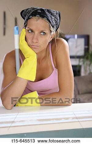 Stock Image - woman in her 20's taking a break from doing chores looking out of window looking depressed. Fotosearch