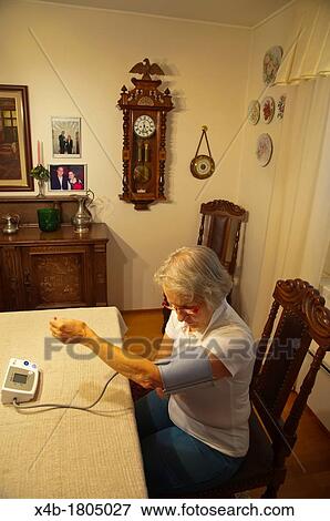 Woman in her early 70s using blood pressure monitor Finland Europe View Large Photo Image Stock Photo - Woman in her early 70s using blood pressure monitor Finland Europe. Fotosearch