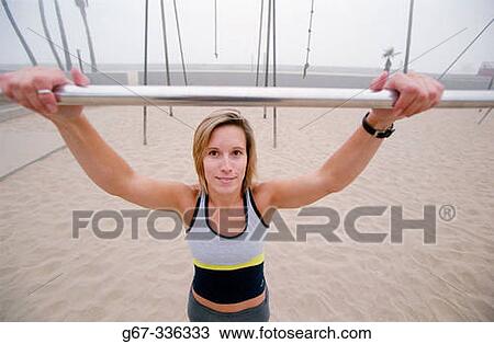 Stock Image - Woman in her mid 20's doing pull ups. Venice. California. USA.. Fotosearch