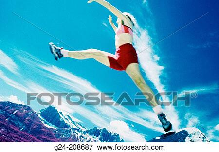 Woman in long jump stride between boulders. Banff NP. Canada View Large Photo Image Stock Photo - Woman in long jump stride between boulders. Banff NP. Canada. Fotosearch