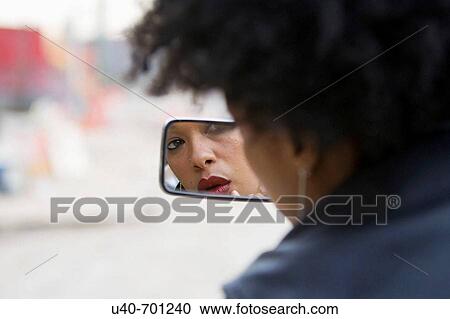 Stock Image - Woman in motorcycle mirror. Fotosearch