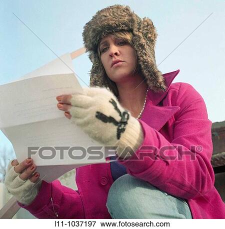 Stock Photo - Woman in pink coat and ushanka, reading letter. Fotosearch