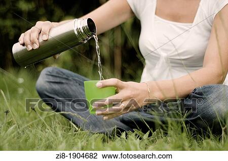 Woman in the park, pouring water from a thermos View Large Photo Image Stock Image - Woman in the park, pouring water from a thermos. Fotosearch