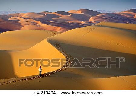 Stock Image - Woman in the sand dunes of the empty quarter desert. United Arab Emirates, UAE, Abu Dhabi, Liwa Oasis, Moreeb Hill, Tal Mireb. Model Released.. Fotosearch