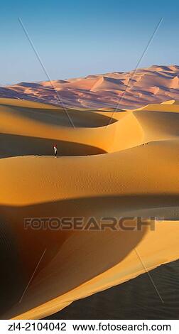Stock Image - Woman in the sand dunes of the empty quarter desert. United Arab Emirates, UAE, Abu Dhabi, Liwa Oasis, Moreeb Hill, Tal Mireb. Model Released.. Fotosearch