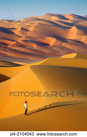Stock Image - Woman in the sand dunes of the empty quarter desert. United Arab Emirates, UAE, Abu Dhabi, Liwa Oasis, Moreeb Hill, Tal Mireb. Model Released.. Fotosearch