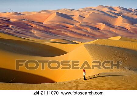 Stock Image - Woman in the sand dunes of the empty quarter desert. United Arab Emirates, UAE, Abu Dhabi, Liwa Oasis, Moreeb Hill, Tal Mireb. Model Released.. Fotosearch