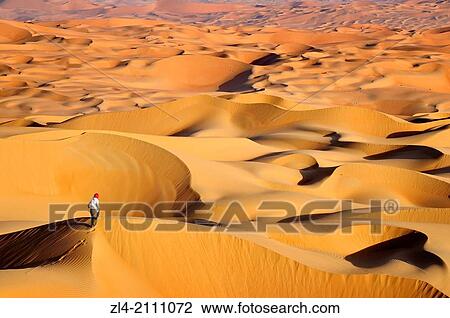 Stock Image - Woman in the sand dunes of the empty quarter desert. United Arab Emirates, UAE, Abu Dhabi, Liwa Oasis, Moreeb Hill, Tal Mireb. Model Released.. Fotosearch