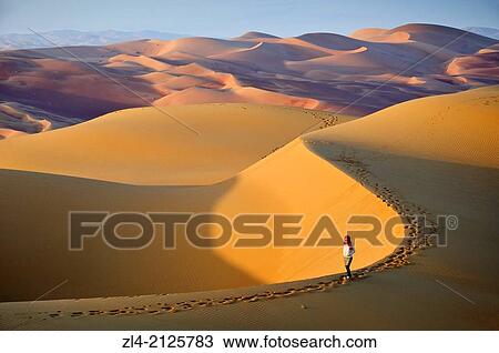 Stock Image - Woman in the sand dunes of the empty quarter desert. United Arab Emirates, UAE, Abu Dhabi, Liwa Oasis, Moreeb Hill, Tal Mireb. Model Released.. Fotosearch