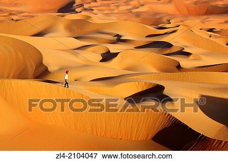 Stock Photo - Woman in the sand dunes of the empty quarter desert. United Arab Emirates, UAE, Abu Dhabi, Liwa Oasis, Moreeb Hill, Tal Mireb. Model Released.. Fotosearch