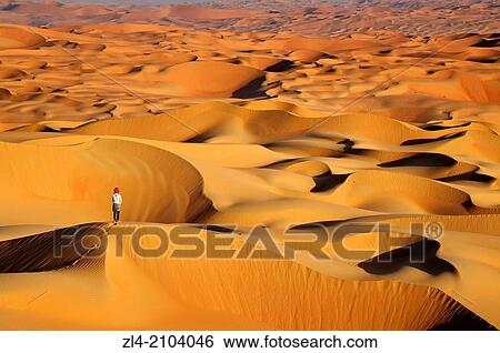 Stock Photograph - Woman in the sand dunes of the empty quarter desert. United Arab Emirates, UAE, Abu Dhabi, Liwa Oasis, Moreeb Hill, Tal Mireb. Model Released.. Fotosearch