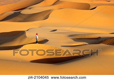 Stock Photography - Woman in the sand dunes of the empty quarter desert. United Arab Emirates, UAE, Abu Dhabi, Liwa Oasis, Moreeb Hill, Tal Mireb. Model Released.. Fotosearch