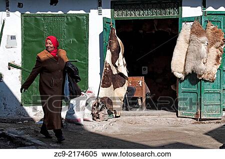 Woman in traditional clothing passing by a animal hides shop in the medina streets, Tetuan, Morocco. View Large Photo Image Stock Photography - Woman in traditional clothing passing by a animal hides shop in the medina streets, Tetuan, Morocco.. Fotosearch