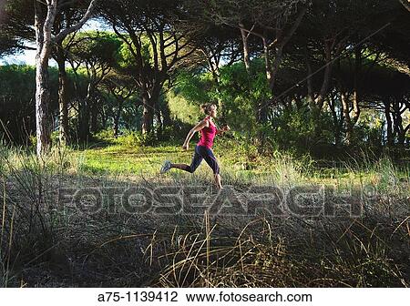 Stock Image - Woman jogging in forest. Fotosearch
