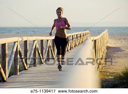 Stock Photo - Woman jogging on boardwalk. Fotosearch