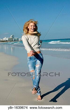 Picture - woman jumping next to seaside. Fotosearch