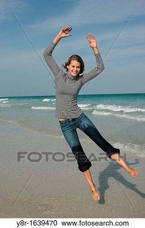 Stock Image - woman jumping next to seaside. Fotosearch