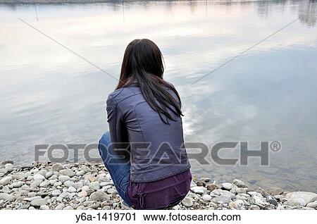 Woman kneeling by lake looking at distance View Large Photo Image Stock Image - Woman kneeling by lake looking at distance. Fotosearch