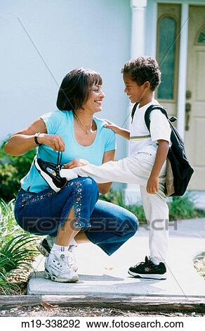 Stock Image - Woman lacing up shoes to her son. Fotosearch