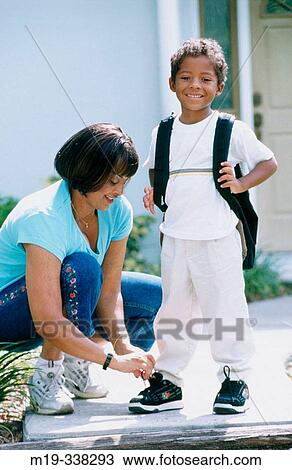 Stock Image - Woman lacing up shoes to her son. Fotosearch