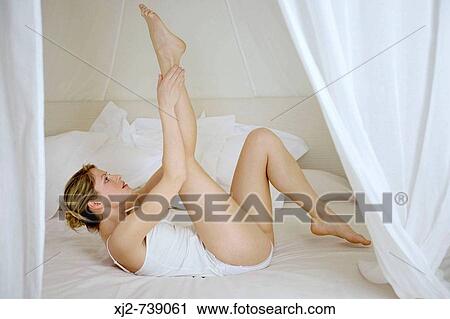 Woman laying on the bed with legs up View Large Photo Image Stock Image - Woman laying on the bed with legs up. Fotosearch