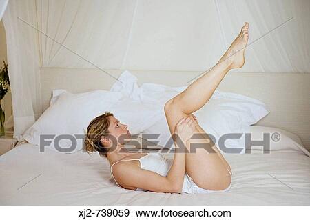 Woman laying on the bed with legs up View Large Photo Image Stock Photo - Woman laying on the bed with legs up. Fotosearch