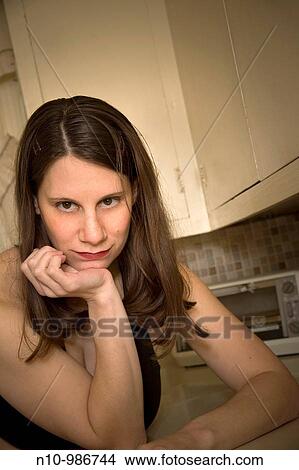Picture - Woman leaning on her kitchen counter. Fotosearch