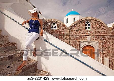 Woman leaning on the wall in front of a blue domed church in Oia town, Santorini, Cyclades Islands, Greek Islands, Greece, Europe. View Large Photo Image Stock Photo - Woman leaning on the wall in front of a blue domed church in Oia town, Santorini, Cyclades Islands, Greek Islands, Greece, Europe.. Fotosearch