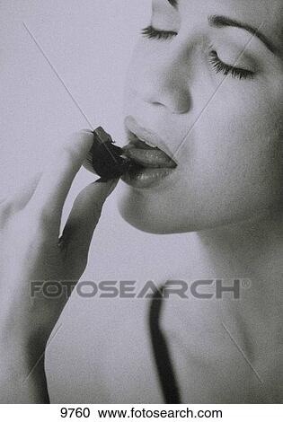 Stock Image - Woman licking a chocolate with eyes closed. Fotosearch