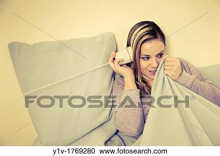 Stock Image - Woman? listening? on a paper cup telephone. Fotosearch