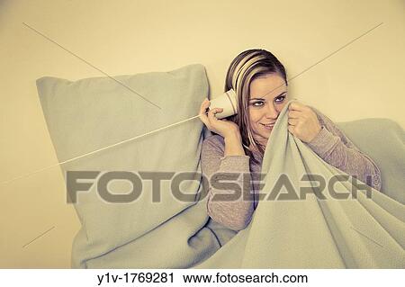 Stock Image - Woman? listening? on a paper cup telephone. Fotosearch