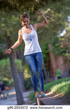 Woman listens music with earphones in a park. View Large Photo Image Stock Image - Woman listens music with earphones in a park.. Fotosearch