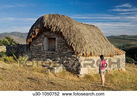 Stock Image - Woman looking at a tradicional cabin in Navalosa, Sierra De Gredos? vila Castilla y Le? n Spain. Fotosearch