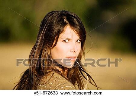 Stock Image - Woman looking at camera in a wheat of field. Fotosearch