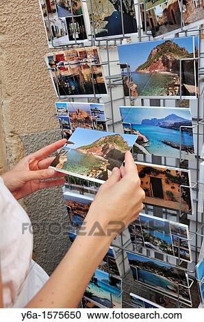 Stock Image - Woman looking at postcards, Alcudia old town, Mallorca, Spain, Europe. Fotosearch