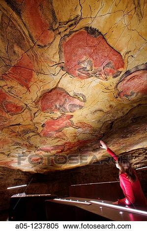 Stock Photography - Woman looking at the paintings Bisons in Altamira's reproduction cave Neo Cave Upper Paleolithic cave paintings Altamira museum UNESCO World Heritage Santillana del Mar Spain. Fotosearch